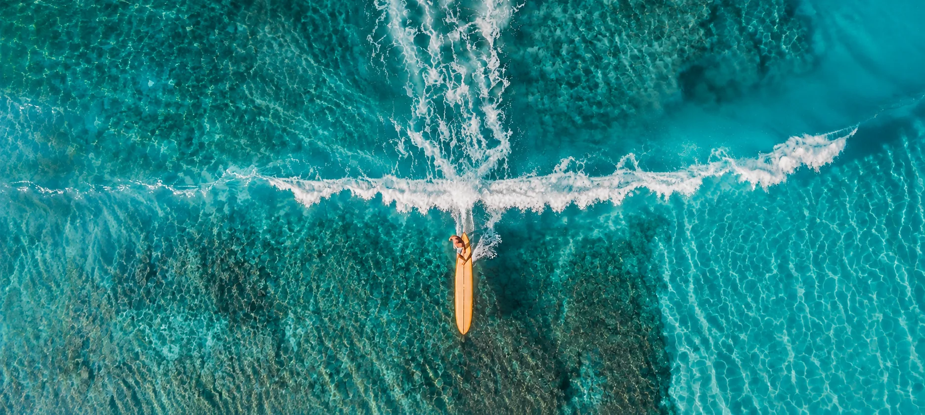 Surfer floating in clear turquoise Pacific water